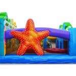 Colorful inflatable play structure with a large red and orange starfish in the center, surrounded by blue, green, and purple sections—perfect for children's entertainment at bounce house Long Island parties or NY events.