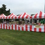 Red and white striped tents form a row on a grassy area, serving popcorn, hot dogs, and hamburgers—perfect for any celebration. For more fun, add a bounce house Long Island party rentals can provide to complete your NY event experience.
