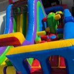 A colorful inflatable obstacle course called "Radical Run II," featuring slides, climbing areas, and various obstacles in bright blue, yellow, green, red, and purple—perfect for party rentals Long Island or bounce house fun in NY.