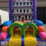 Colorful inflatable bounce house labeled "Fun House" with two yellow slides and arched entrances, set up outdoors near a building—perfect for NY parties and available from bounce house Long Island party rentals.
