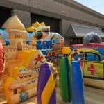 Inflatable play structures featuring colorful sandcastles, surfboards, a lifeguard car, and a smiling sun wearing sunglasses—perfect for bounce house Long Island party rentals in NY.