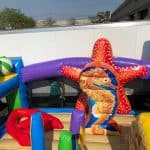 Colorful inflatable bounce house Long Island with an undersea theme, featuring a red and orange starfish, a seahorse, large beach ball, and bright structures—perfect for party rentals Long Island. A child is visible in the background.