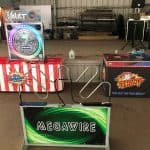 Three arcade game stations are set up indoors—perfect for party rentals Long Island, NY. The front game is “MEGAWIRE,” while the back games, “The Vault” and “Strike A Light,” all feature bright lights and colorful displays.