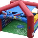 The "Game Zone" is a colorful inflatable play structure, perfect for children's activities. This bounce house Long Island, NY features red, blue, yellow, and green sections with a pointed roof and soft barriers inside for safe fun.