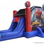 An inflatable Spider-Man bounce house with two red slides, Spider-Man graphics, and two round decorations featuring Spider-Man’s face on top of the entrance columns—perfect for party rentals Long Island celebrations.
