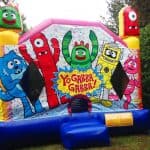 Colorful inflatable bounce house featuring "Yo Gabba Gabba!" characters with a blue entrance and trees in the background. Perfect for party rentals Long Island, this fun attraction displays "Yo Gabba Gabba!" in a yellow starburst.