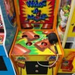 Arcade Whac-A-Mole game machine with a large mallet attached by a cord, perfect for party rentals Long Island, NY. Colorful illustrations of moles and mallets decorate the surface, featuring three holes where moles pop up for fun competition.