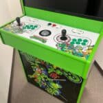 A bright green Teenage Mutant Ninja Turtles arcade machine with two joysticks, multiple buttons, and colorful character artwork—perfect for NY party rentals Long Island or any bounce house Long Island celebration.