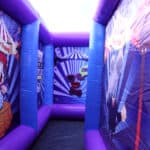 A colorful inflatable maze with cartoon circus-themed images, perfect for NY events. Mainly purple and blue with a bright, open top, this bounce house Long Island favorite adds fun to any party rentals Long Island lineup.