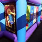 Colorful inflatable maze walls featuring vivid graphics and motivational text, with sunlight casting shadows across the structure, set outdoors on a paved surface—perfect for party rentals Long Island events.