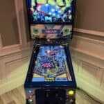 A “Tommy” pinball machine stands against a wall in NY, with colorful lights and graphics featuring The Who on its display, set to free play mode. The playfield shows intricate pinball artwork and various game elements.