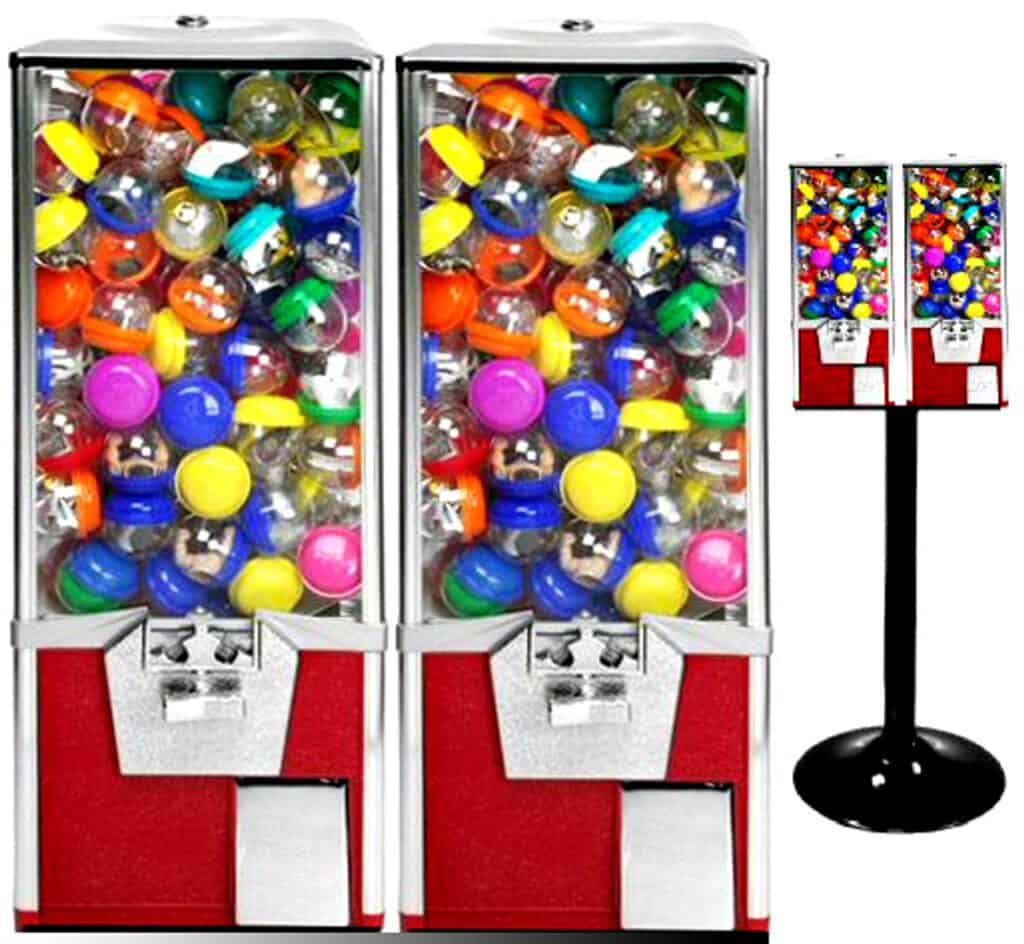 Two red and silver vending machines filled with colorful plastic toy capsules are shown side by side—perfect additions for party rentals Long Island, NY. A stand with two similar vending machines is also visible to the right.
