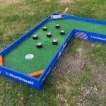 A mini-golf course designed like a hockey rink, with green turf, black hockey pucks as obstacles, and Northwell branding—perfect for party rentals Long Island or pairing with a bounce house Long Island, NY for sports-themed events.