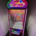 A brightly lit "Sweet Shoppe" claw machine with neon pink and purple lights stands in a corner. Perfect for party rentals Long Island, this candy-themed game promises "Winner Every Time" and adds sweet fun to any NY celebration.
