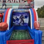 Inflatable football-themed game in red, white, and blue—perfect for party rentals Long Island. Features a football field design, basketball on the left, football on the right, and backdrop of a player aiming at circular targets.