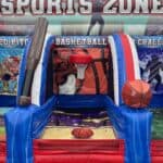 An inflatable sports game, perfect for party rentals Long Island, NY, features a basketball section with a large hoop, ball, and giant inflatable bat against a vibrant "SPORTS ZONE" backdrop with sports-themed graphics.