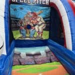 Inflatable "Speed Pitch" game featuring baseball artwork with a pitcher, catcher, and umpire—perfect for party rentals Long Island. Includes a throw hole and stadium scene on the floor for extra fun at your next event!.