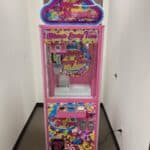 A colorful “Sweet Shoppe” candy claw machine stands in a narrow hallway, perfect for NY parties. Decorated with bright, candy-themed graphics and "Winner Every Time" text, it pairs well with bounce house Long Island party rentals.
