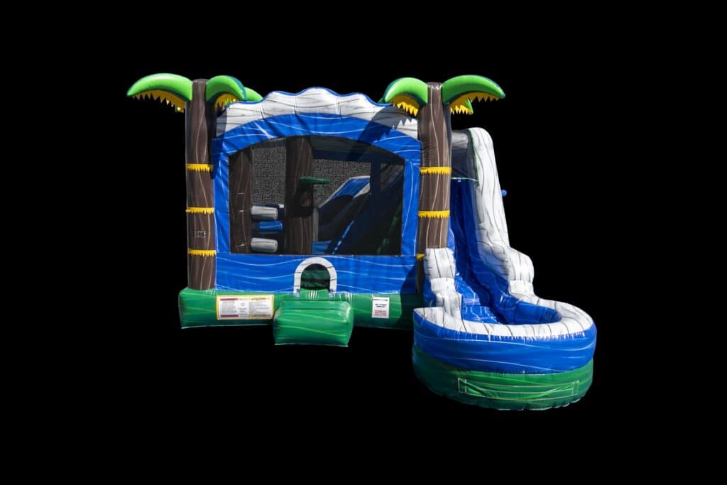 The 7 in 1 Tropical Combo is an inflatable bounce house with a slide, blue, green, and white colors, palm tree corners, and a black background—perfect for party rentals in Long Island, NY.