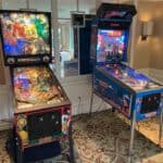 Two vibrant Custom Wrapped Claw Machines stand side by side in a carpeted room with beige walls and a large mirror, perfect for party rentals on Long Island or event fun in NY.