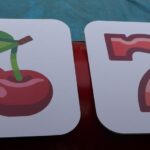 Two large cards—one with red cherries, the other with a red number seven—both featuring rounded corners, sit side by side on a red surface. Perfect inspiration for a bounce house Long Island or party rentals NY event design.
