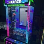 A brightly lit arcade game machine called "Brick Attack" features neon lights, a joystick, and buttons—perfect for party rentals Long Island. Inside its glass case, a vertical screen displays a Tetris-like puzzle game.