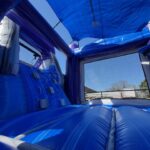 Interior view of an inflatable bounce house Long Island, NY, with blue and purple walls, a climbing wall, and mesh windows. Sunlight filters inside the bounce house floor—perfect for your next party rentals Long Island event.