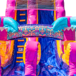 A colorful inflatable slide with pink, yellow, and blue sections, decorated with tropical patterns and palm tree shapes, stands against a white background. The slide features a central climbing ladder.