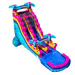 A large inflatable water slide with bright blue, pink, and yellow colors, decorated with palm tree designs. The slide leads into a shallow splash pool at the bottom.